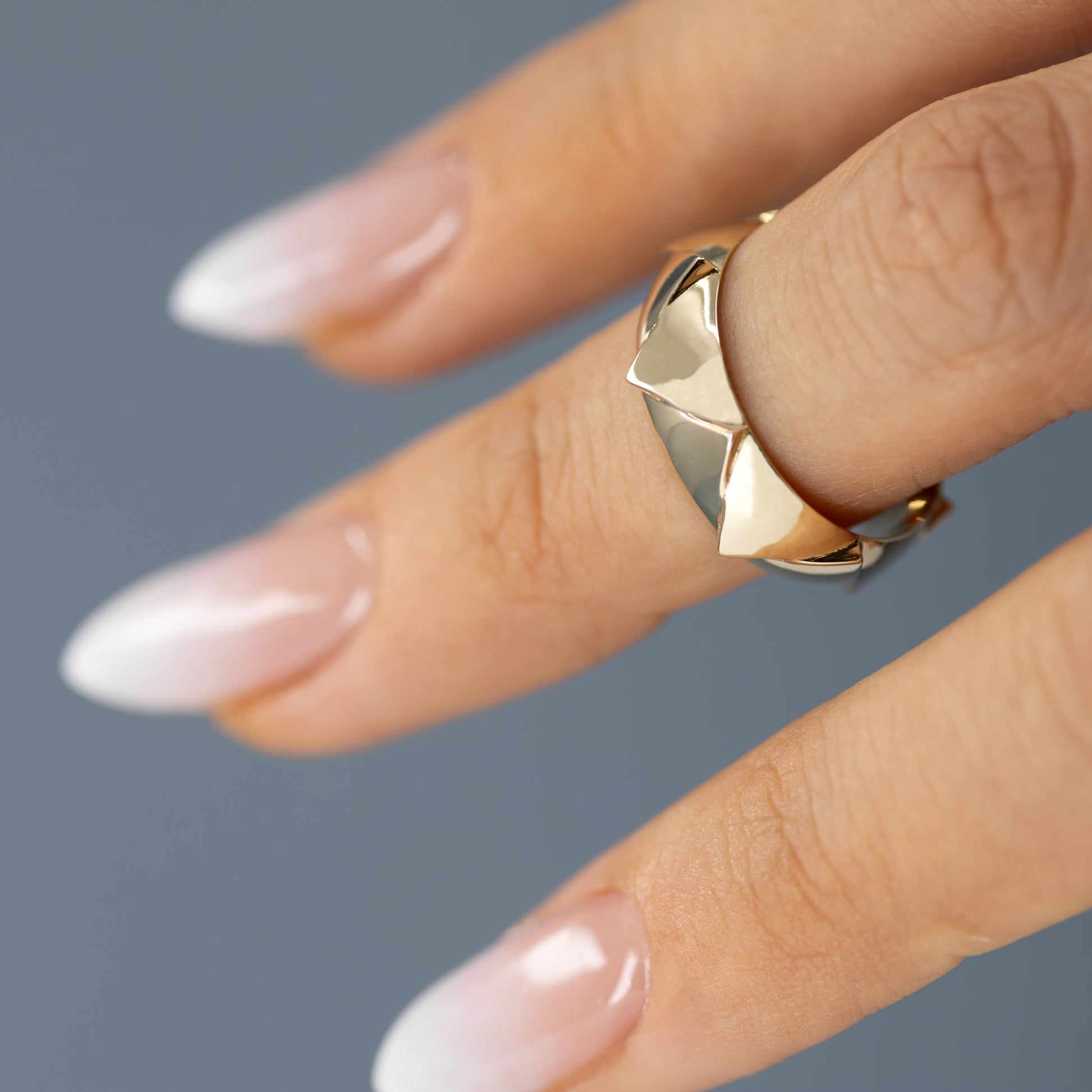 Elegant hand adorned with a solid 14k gold ring featuring sharp, crown-inspired facets. The bold design reflects light beautifully, emphasizing its regal craftsmanship. Band width: 5.7mm