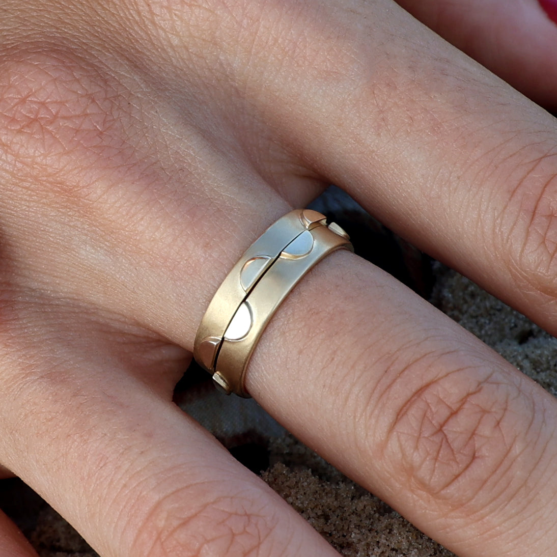 Close-up of two solid 14k gold rings stacked together on a hand. The rings feature circular cutout designs and a polished finish, creating a modern and playful aesthetic.