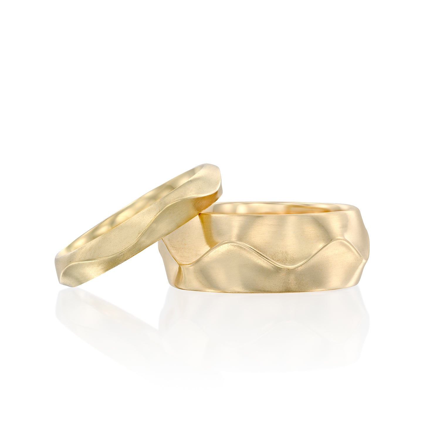 Two solid 14k gold rings with a ruffled texture, one slimmer and one wider. The polished bands showcase a flowing, ribbon-like design, blending elegance with bold sophistication. 