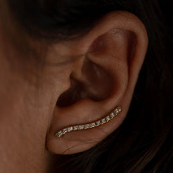 A solid 14k gold curved earring, adorned with a row of carré-cut lab-grown white diamonds. The elegant design follows the natural contour of the ear, creating a subtle yet striking look.