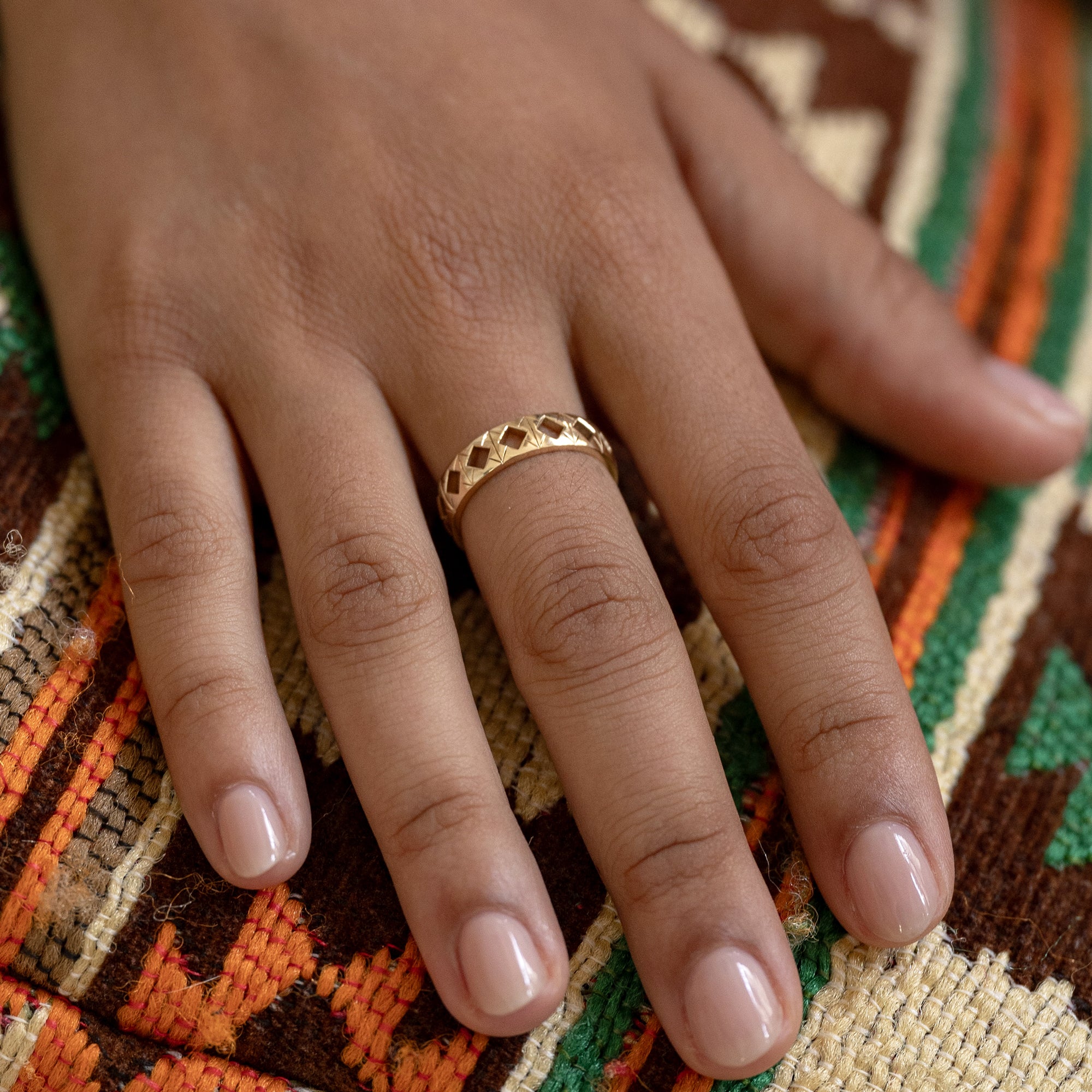 A hand adorned with the Tiling Ring, its tessellated design featuring sharp engraved lines and negative spaces, creating a harmonious blend of vintage charm and modern elegance. Photographed in solid 14k gold. Band width: 5mm.